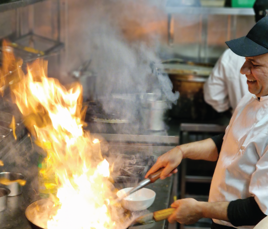 Indian Tapas from Papa J's Luton, dine in and takeaway commercial kitchen with a chef cooking, the pan full of flames
