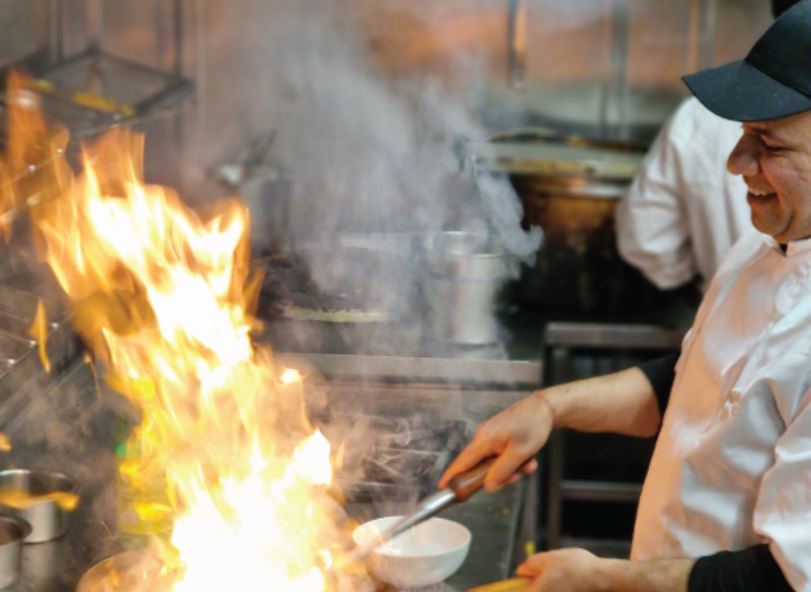 Chef cooking in a kitchen, pan hes cooking in has flames